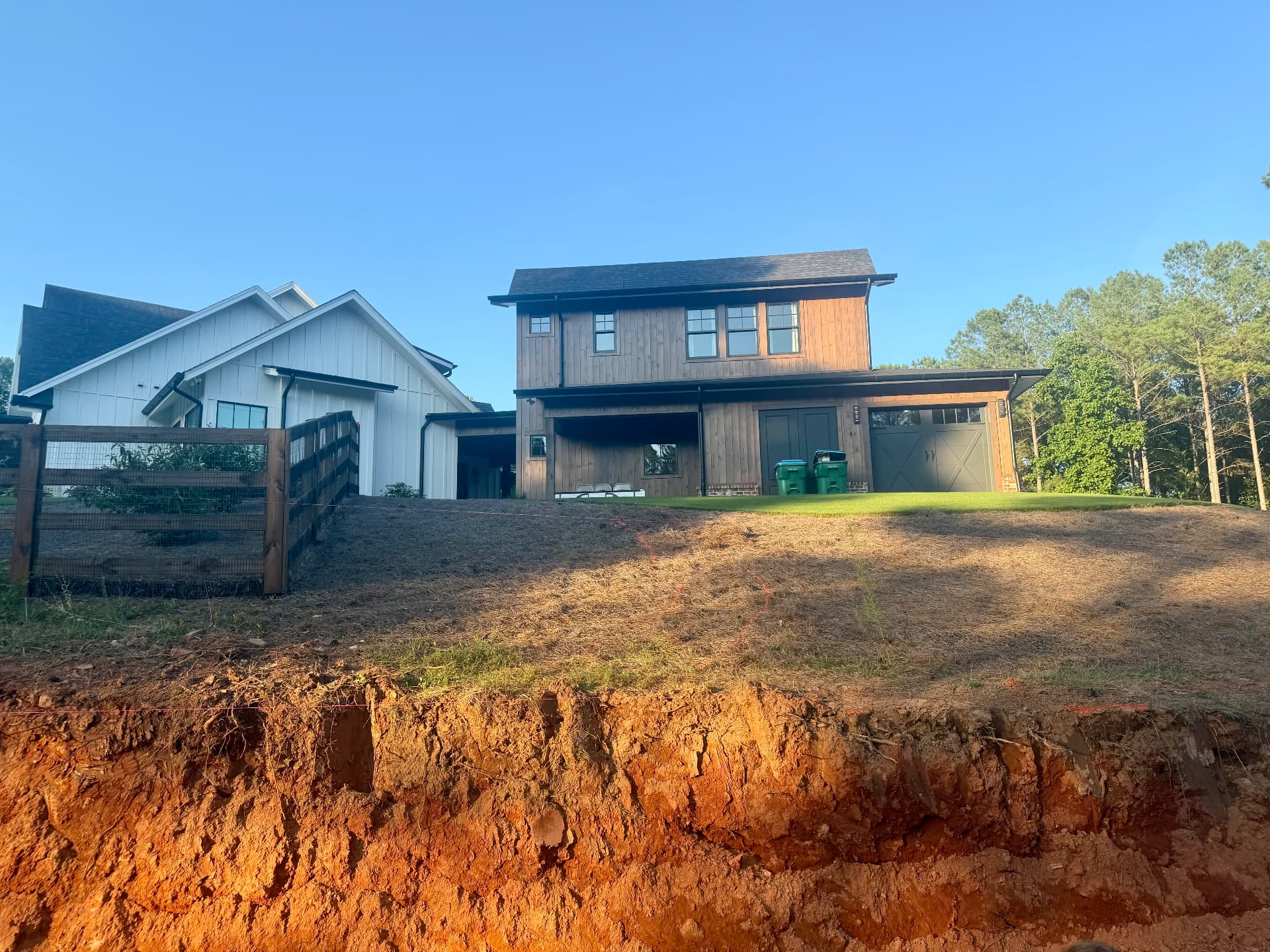 Before: modern farmhouse with an eroding red clay bank and no usable front approach